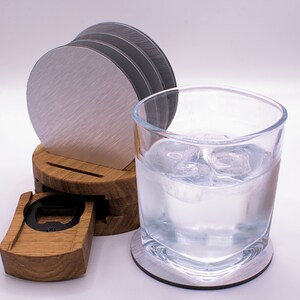 May include: A wooden coaster set with a built-in bottle opener. The set includes four silver coasters and a glass of water with ice.