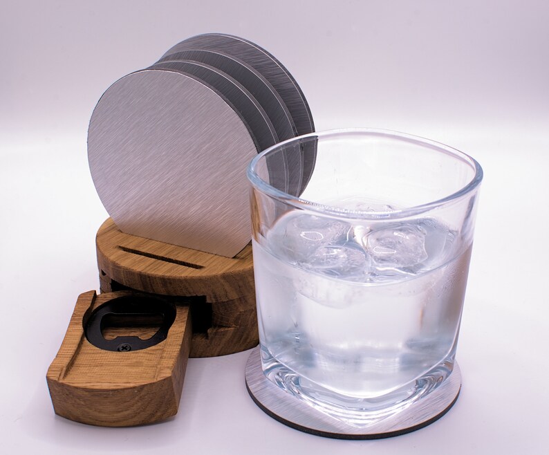 May include: A wooden coaster set with a built-in bottle opener. The set includes four silver coasters and a glass of water with ice.