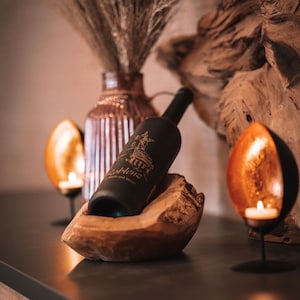 Dieser elegante Weinflaschenhalter aus massivem Teakholz bietet Platz für drei Weinflaschen und verbindet natürliche Schönheit mit praktischem Design. Jeder Halter wird aus einem einzigartigen Stück Holz gefertigt – keine Maserung gleicht der anderen, sodass du immer ein echtes Unikat erhältst.

Das warme, goldbraune Teakholz sorgt für eine edle, natürliche Optik, die in jeder Umgebung ein Blickfang ist – ob in der Küche, im Wohnzimmer oder im Weinkeller.
