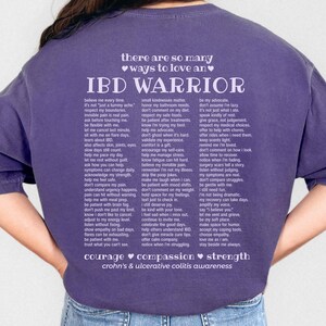 May include: A purple short-sleeved t-shirt with the words "IBD WARRIOR" in white, along with a list of supportive phrases. The shirt also features the words "courage, compassion, strength" and "crohn's & ulcerative colitis awareness."