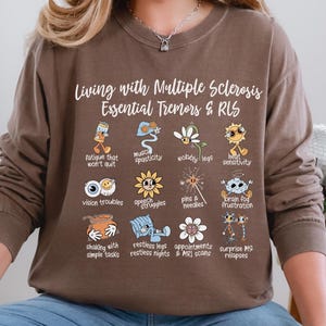 May include: A brown long-sleeve shirt with the text "Living with Multiple Sclerosis Essential Tremors & RLS" and illustrated icons representing symptoms. The icons include fatigue, muscle spasticity, vision troubles, and more.
