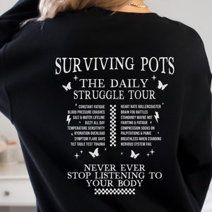 Puede incluir: Sudadera negra con texto blanco que dice "Surviving Pots + The Daily Struggle Tour" y enumera los síntomas del POTS, incluyendo fatiga constante, caídas de presión arterial, montaña rusa del ritmo cardíaco, niebla cerebral, y más. El texto también incluye la frase "Nunca dejes de escuchar a tu cuerpo".