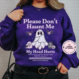 Puede incluir: Una sudadera morada con el texto "Please Don't Haunt Me" y un gráfico de fantasma. El diseño incluye murciélagos, lápidas y la frase "My Head Hurts". La sudadera tiene mangas largas y cuello redondo.