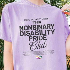 May include: A light purple t-shirt featuring the black text LOVE. WITHOUT. LIMITS. THE NONBINARY DISABILITY PRIDE CLUB. Below the text is a paragraph about living authentically and a small heart icon with nonbinary and disability pride flag colors.