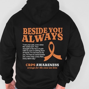 May include: Black hoodie featuring the words "BESIDE YOU ALWAYS" in orange. An orange awareness ribbon and a quote are below the text. The hoodie also includes the text "CRPS AWARENESS orange for the ones we love."