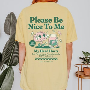 May include: Yellow t-shirt with a cartoon brain and jar design. The text on the shirt reads "Please Be Nice To Me", "My Head Hurts but I'm here and I'm being really BRAVE about it." and "Have a Nice Day!"