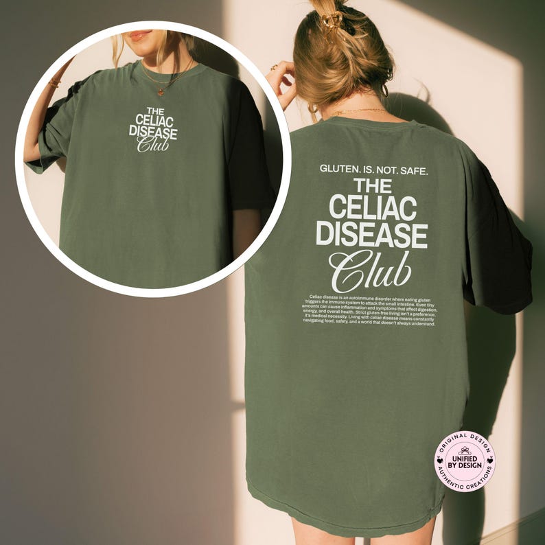 Op de afbeelding: Olijfgroen T-shirt met witte tekst. De voorkant heeft "THE CELIAC DISEASE Club", en de achterkant heeft "GLUTEN. IS. NOT. SAFE." en een beschrijving van Coeliakie. Het T-shirt heeft een relaxte pasvorm.