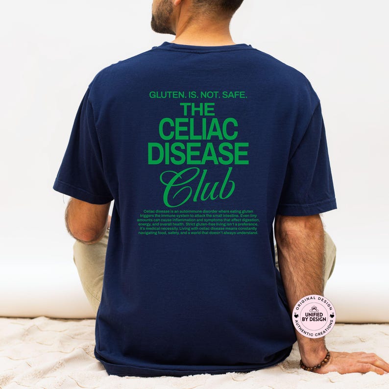 Op de afbeelding: Marineblauw T-shirt met groene tekst: "GLUTEN. IS. NOT. SAFE. THE CELIAC DISEASE Club." Het T-shirt bevat ook een beschrijving van coeliakie. Casual stijl.