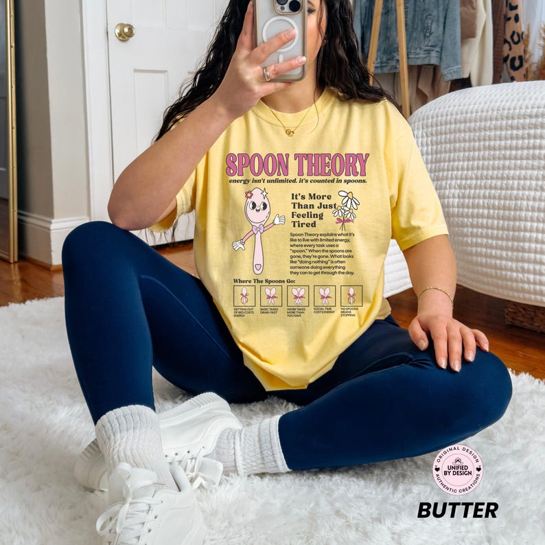 May include: Yellow t-shirt with the text "SPOON THEORY" and a cartoon spoon illustration. The shirt also includes the text "It's More Than Just Feeling Tired" and a diagram. The word "BUTTER" is printed at the bottom.