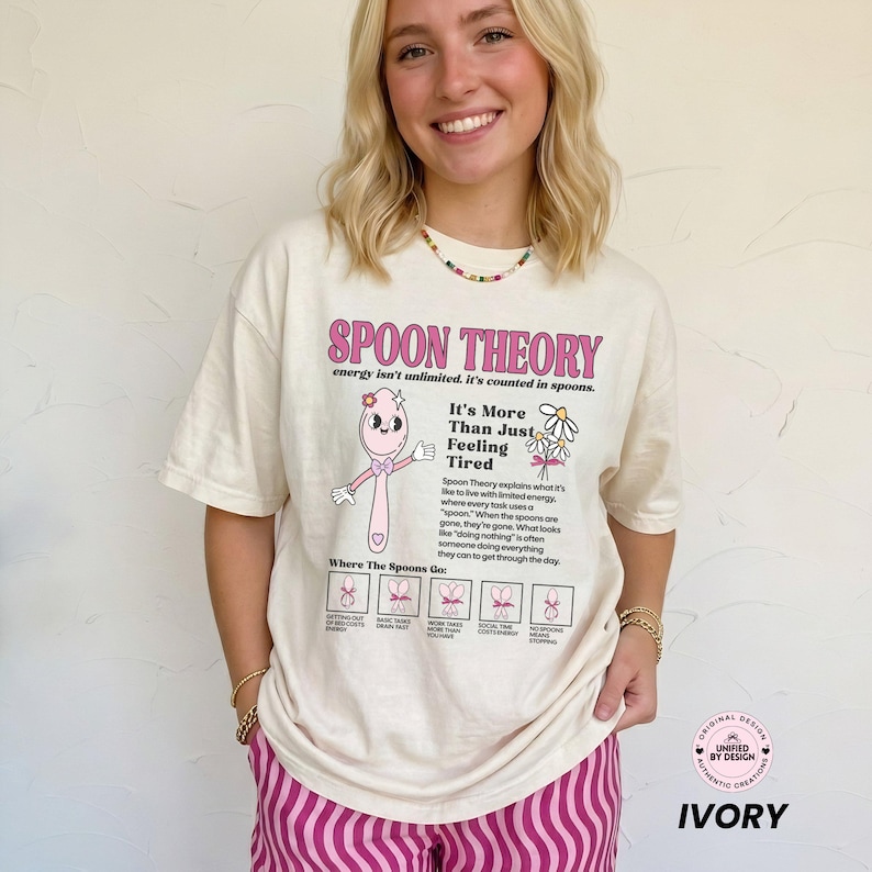 May include: An off-white t-shirt featuring a pink cartoon spoon character and the text Spoon Theory, energy isn't unlimited, it's counted in spoons. It's More Than Just Feeling Tired, and a diagram explaining spoon usage with small icons.