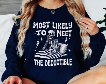 May include: A navy blue sweatshirt with a white graphic of a skeleton in bed. The text on the sweatshirt reads "Most Likely To Meet The Deductible".