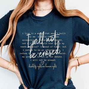 May include: A navy blue t-shirt with a white graphic print that reads "I will not be erased. Disability rights are human rights." The graphic print is centered on the shirt and is surrounded by a white border.
