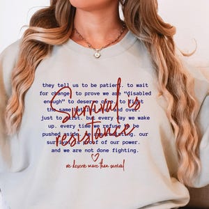 May include: A light blue sweatshirt with the text "they tell us to be patient. to wait for change to prove we are "disabled enough" to deserve care. to fight the same battles and over. just to exist. but every day we wake up. every time we refuse to be pushed aside. we are resisting. survival is proof of our power. and we are not done fighting. ♡ we deserve more than survival" printed in red.