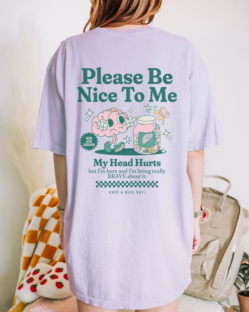 May include: Purple t-shirt with a graphic of a brain holding a jar with a heart and the text "Please Be Nice To Me", "Head Ache Survivor", "My Head Hurts but I'm here and I'm being really BRAVE about it. HAVE A NICE DAY!"