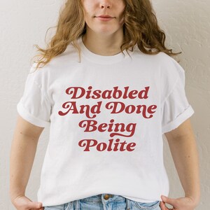 Peut inclure: T-shirt blanc avec un texte rouge qui dit "Disabled And Done Being Polite".