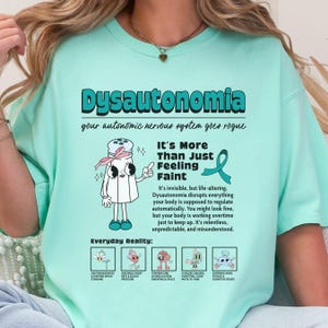 May include: A mint green t-shirt featuring a graphic with the text Dysautonomia, your autonomic nervous system goes rogue, It's More Than Just Feeling Faint, and Everyday Reality. The design includes a salt shaker character and five small icons.