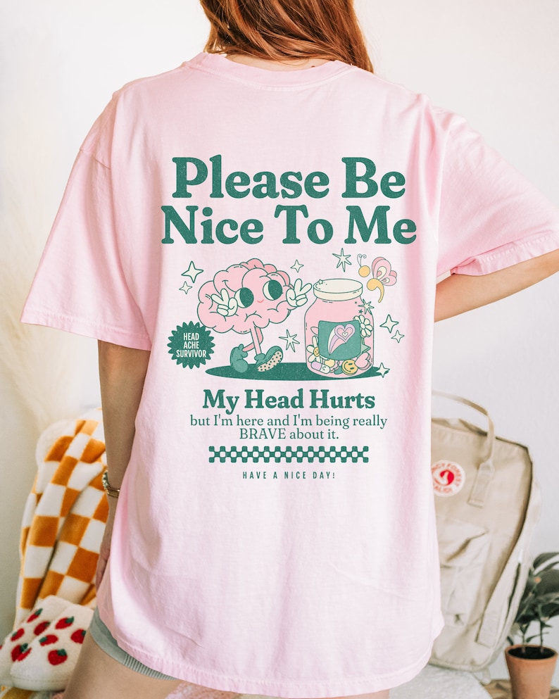 May include: Pink t-shirt with a green cartoon brain and a jar with hearts and stars. The text on the shirt reads "Please Be Nice To Me", "Head Ache Survivor", "My Head Hurts but I'm here and I'm being really BRAVE about it. HAVE A NICE DAY!"