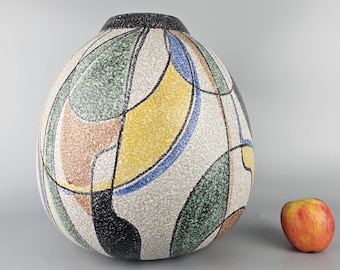 May include: A large, round ceramic vase with a white background and abstract geometric designs in black, green, yellow, and blue. The vase has a textured surface.