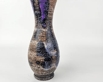 Może przedstawiać: Brązowy ceramiczny wazon z pstrokatą glazurą i fioletowymi i niebieskimi akcentami. Wazon ma wąską szyjkę i zaokrąglone dno.