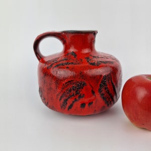 A West German Fat Lava vase/jug made by Gräflich Ortenburg. The vase/jug is red and black and is numbered 619.