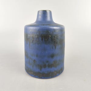 Puede incluir: Un jarrón de cerámica azul con detalles de esmalte negro. El jarrón tiene un cuerpo redondeado y un cuello estrecho.