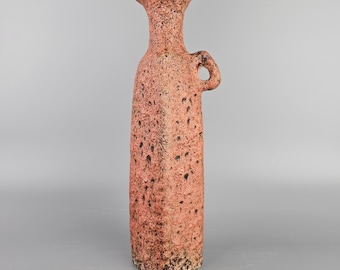 May include: A tall, pink ceramic vase with a textured surface and a handle. The vase has a square base and a narrow neck.