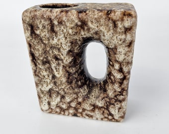 May include: A brown and white ceramic vase with a unique, abstract design. The vase has a square shape with a cutout on one side.
