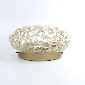 May include: A flush mount ceiling light fixture featuring a cluster of amber-tinted, spherical glass bubbles arranged in a dome shape. The glass elements are mounted onto a circular, metallic gold-toned base with small visible screws.