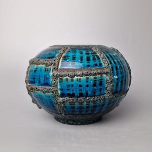 Könnte beinhalten: Eine blaue und braune Keramikvase mit geometrischem Muster. Die Vase hat eine raue, strukturierte Oberfläche.