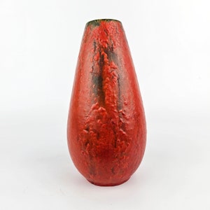 Può includere: Un vaso in ceramica rosso con una superficie testurizzata. Il vaso ha una forma arrotondata a forma di lacrima e un bordo verde scuro.