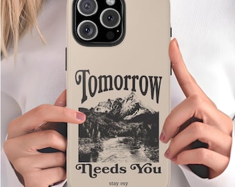May include: A beige phone case with a black and white graphic of a mountain range and the text "Tomorrow Needs You" with the words "stay esy" below.