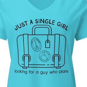 May include: A turquoise V-neck t-shirt with the text "JUST A SINGLE GIRL" and "looking for a guy who plans". The graphic features a suitcase with travel stickers.