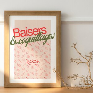 Op de afbeelding: Een ingelijst print met een roze achtergrond en een patroon van rode schelpen. De tekst "Baisers & coquillages" is geschreven in groene en rode letters.