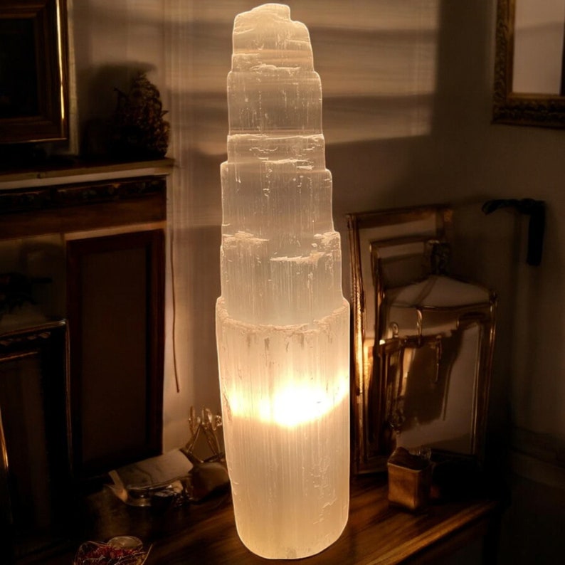 Peut inclure: Une grande lampe en cristal de s&eacute;l&eacute;nite blanche avec une lumi&egrave;re chaude et incandescente &eacute;manant du centre. Le cristal a la forme d'une tour &agrave; plusieurs &eacute;tages.