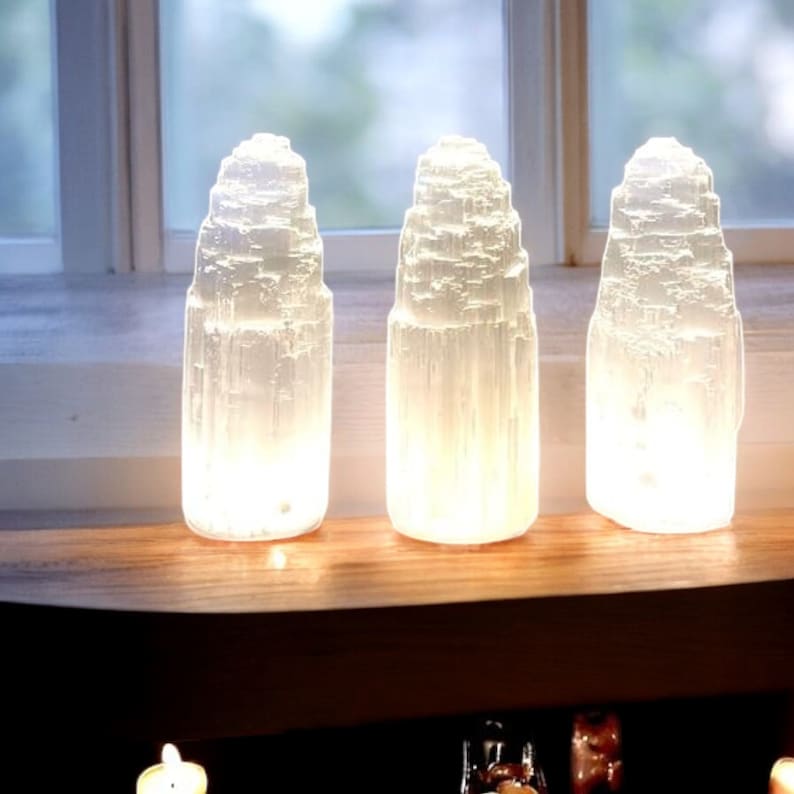 Peut inclure: Trois lampes en cristal de s&eacute;l&eacute;nite blanc sur une &eacute;tag&egrave;re en bois. Les lampes sont allum&eacute;es et brillent.
