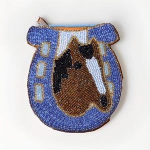 May include: A beaded coin purse in the shape of a horseshoe, featuring a horse head design. The purse is primarily blue with a brown, black, and white horse head. The zipper is light blue.