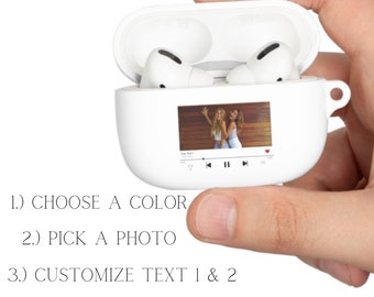 May include: White wireless earbud case with a customisable photo display. The case has a built-in screen that can display a photo, and the user can choose a colour for the case. The text on the case says "1.) CHOOSE A COLOR", "2.) PICK A PHOTO", and "3.) CUSTOMIZE TEXT 1 & 2".