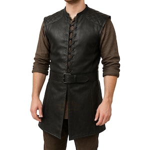 May include: Black leather vest with a quilted shoulder design, a lace-up front, and a belt. The vest is long, reaching the mid-thigh. The model is wearing a brown long-sleeve shirt underneath. The vest is a medieval or renaissance style.