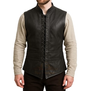 Puede incluir: Chaleco de cuero negro con cordones en la parte delantera y cuello alzado. El chaleco tiene una silueta entallada y presenta costuras y paneles detallados. El chaleco se lleva sobre una camisa beige de manga larga.