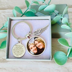 Könnte beinhalten: Ein silberner Schlüsselanhänger mit einem kleinen Foto-Anhänger, der zwei lächelnde Frauen zeigt. Der Anhänger hat eine gravierte Botschaft, die lautet: "Wenn die Nächte kalt sind und die Sterne rar, schließe ich meine Augen und denke an dich. Eine stille Hoffnung, eine stille Träne, ein stiller Wunsch, Dass du hier wärst."