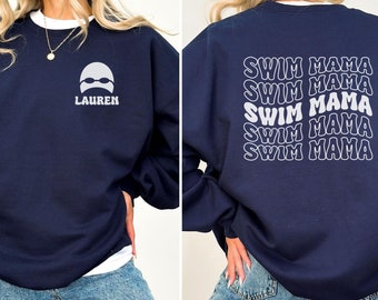 May include: Navy blue sweatshirt with white text and graphics. The front features a swimmer graphic and the name "LAUREN". The back displays "SWIM MAMA" repeated multiple times. A casual, comfortable garment.
