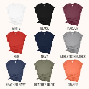 May include: A set of ten t-shirts in various colors, including white, black, maroon, red, navy, athletic heather, heather navy, heather olive, and orange. The shirts are all folded and laid out on a white background.