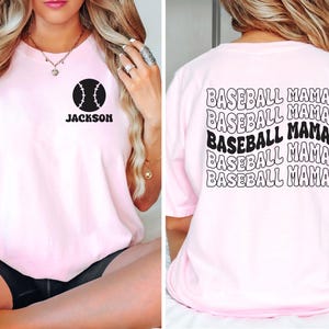 May include: Pink t-shirt with a baseball graphic and the text "Jackson" on the front. The back of the shirt has the text "Baseball Mama" repeated five times in a wavy font.