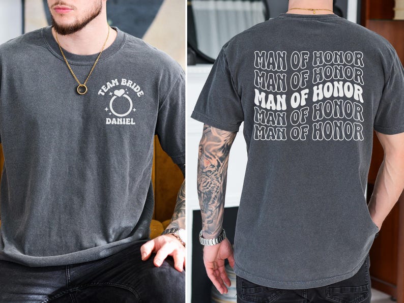 Pode incluir: Camiseta cinza carv&atilde;o com texto branco. A frente diz "TEAM BRIDE" acima de um gr&aacute;fico de anel e "DANIEL" abaixo. A parte de tr&aacute;s da camisa repete "MAN OF HONOR" em um design ondulado. Uma camiseta casual para um casamento.