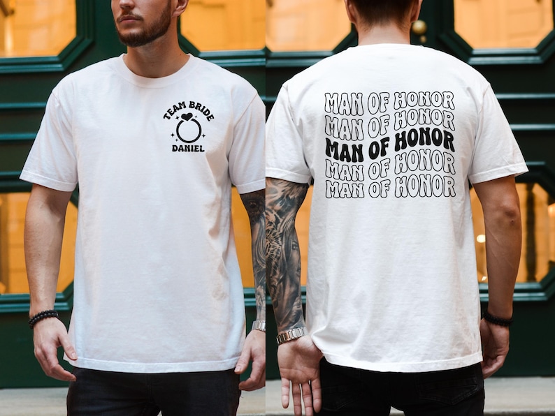 Pode incluir: T-shirts brancas com texto preto. Uma camisa tem "TEAM BRIDE" acima de um gr&aacute;fico de anel e "DANIEL" abaixo. A outra camisa tem "MAN OF HONOR" repetido nas costas. Ambas as camisas s&atilde;o de manga curta.