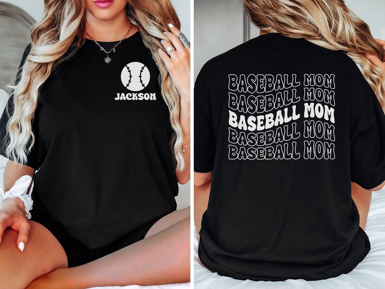 May include: A black t-shirt featuring a white baseball graphic with the name JACKSON on the front left chest. The back of the shirt displays the text BASEBALL MOM repeated five times in a wavy, stacked white font design.