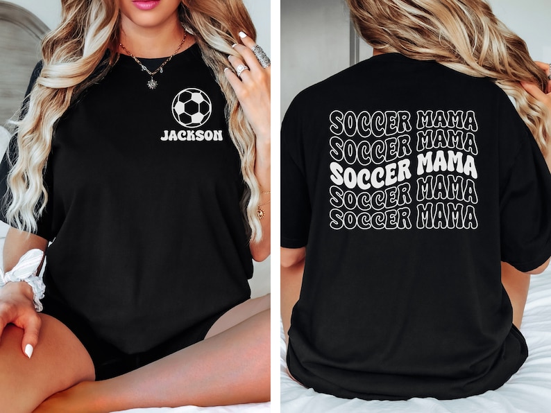 Peut inclure: T-shirt noir avec un motif de ballon de football blanc et le texte "JACKSON" sur le devant. Le dos du t-shirt porte le texte "SOCCER MAMA" r&eacute;p&eacute;t&eacute; cinq fois dans une police de caract&egrave;res r&eacute;tro.