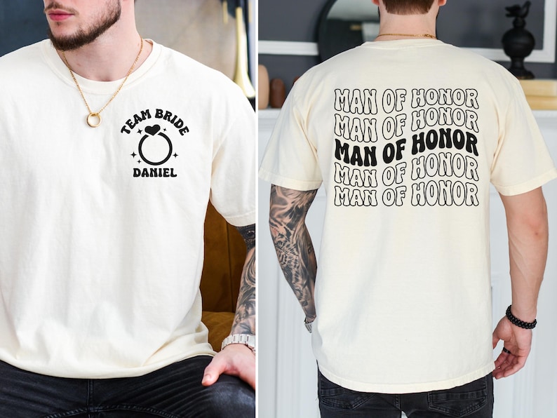 Pode incluir: Camiseta creme com texto e gr&aacute;ficos pretos. A frente apresenta um gr&aacute;fico de anel com as palavras "TEAM BRIDE" acima e "DANIEL" abaixo. A parte de tr&aacute;s da camisa tem as palavras "MAN OF HONOR" repetidas v&aacute;rias vezes.