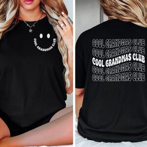 May include: Black t-shirt with the text "COOL GRANDMAS CLUB" in white. The front of the shirt features a smiley face design with the text "COOL GRANDMAS CLUB" in a circular pattern. The back of the shirt repeats the text.