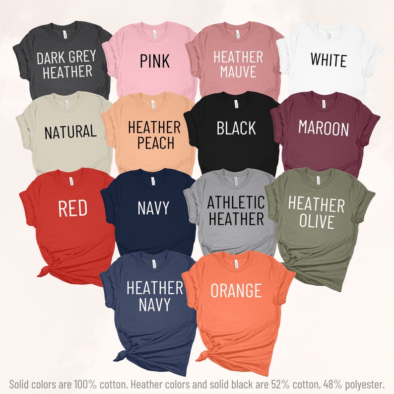 May include: A selection of t-shirts in various colors and styles, including dark grey heather, pink, heather mauve, white, natural, heather peach, black, maroon, red, navy, athletic heather, heather olive, heather navy, and orange. Solid colors are 100% cotton. Heather colors and solid black are 52% cotton, 48% polyester.
